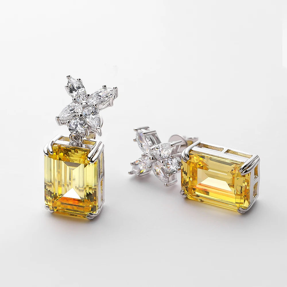 Pair of yellow gemstone earrings with diamond accents on a light gray background