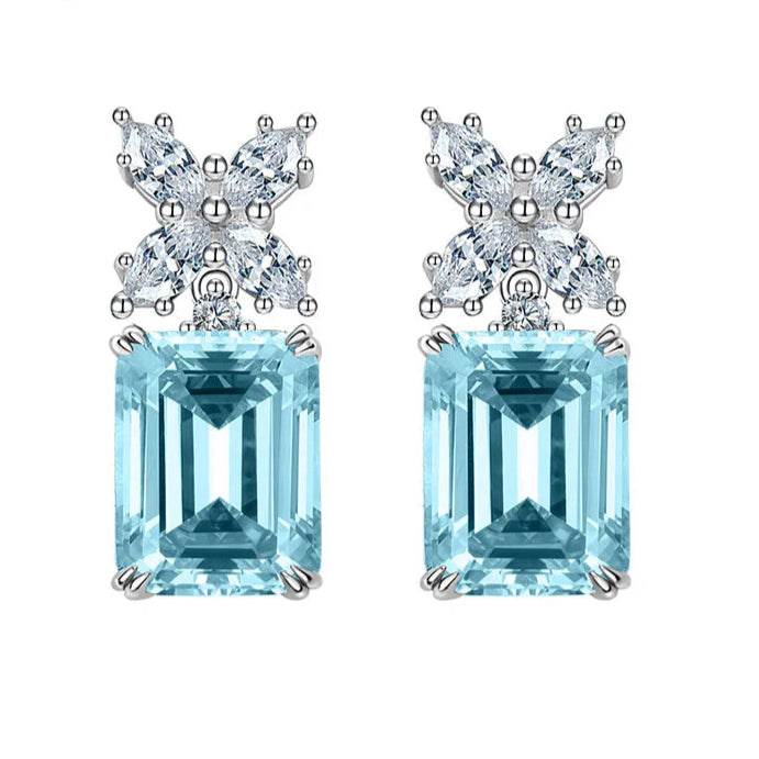 Pair of earrings with blue gemstones and butterfly designs on a white background