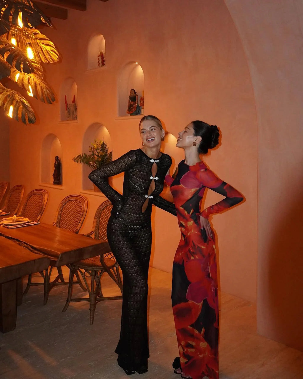 Two women posing in a restaurant with warm lighting and decor.