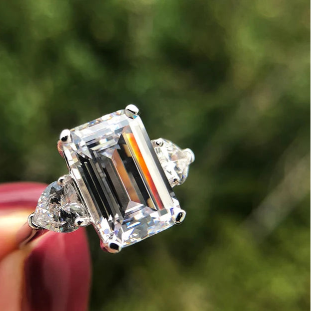 Diamond ring held by a hand with a blurred green background