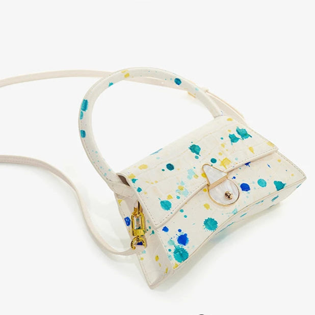 Person holding a floral handbag with a light-colored background