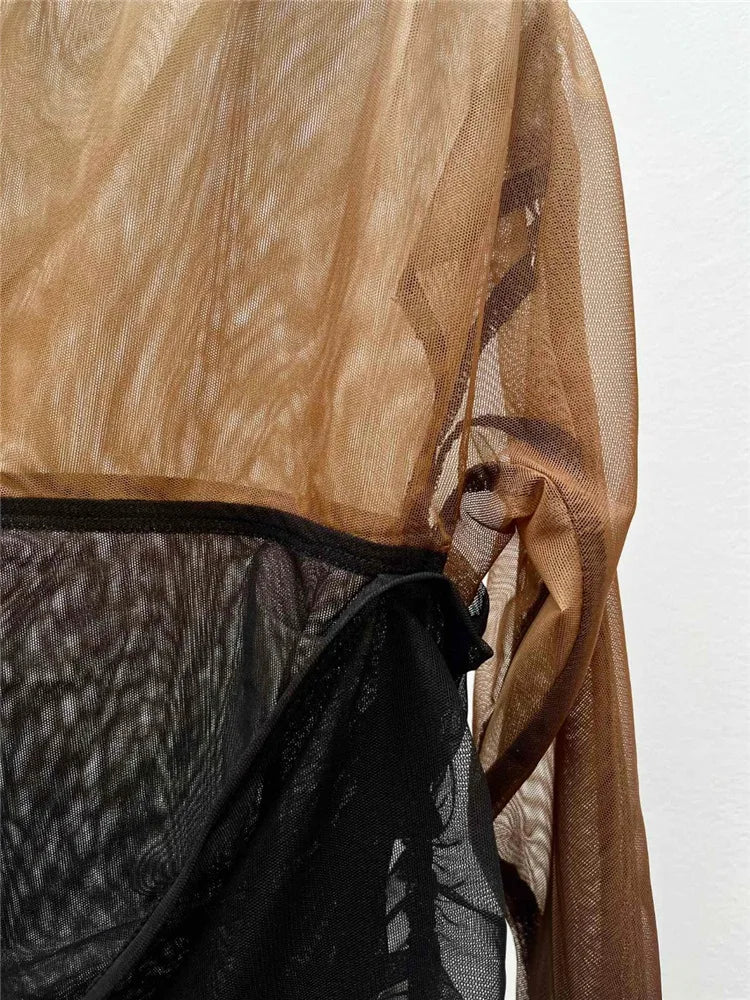 Close-up of a brown sheer fabric draped over a black garment on a white background