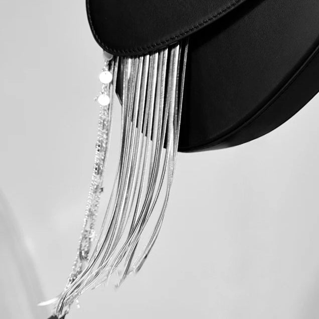 Black handbag with silver tassels on a light gray background