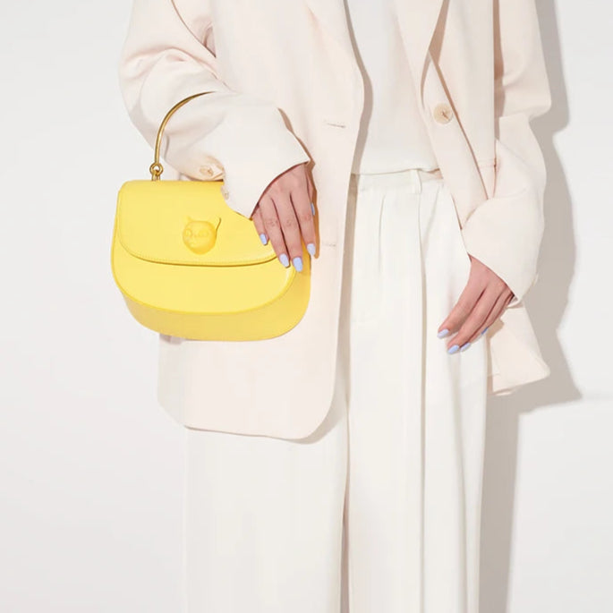 Person holding a yellow handbag with 'Bafelli' branding on a white background