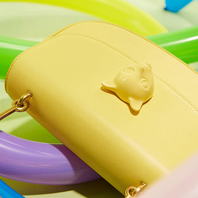 Yellow handbag with a cat emblem on a colorful background, featuring the brand 'Nameless Cat'.