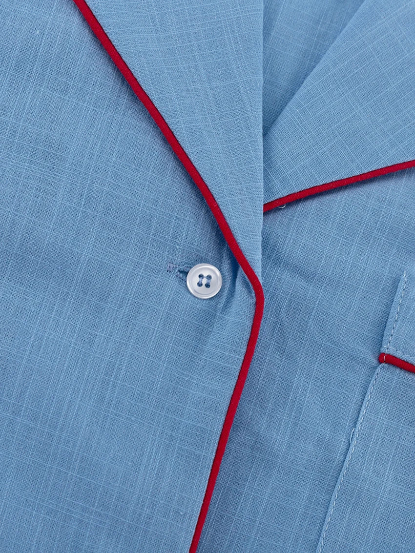 Close-up of a blue fabric with red piping and a button.