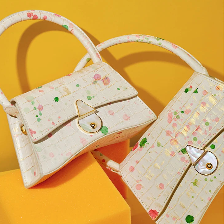 Two decorative handbags with floral patterns on a yellow background, featuring the brand 'Bafelli'.