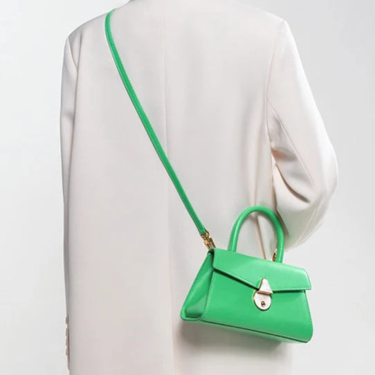 Green handbag worn over shoulder on a white outfit