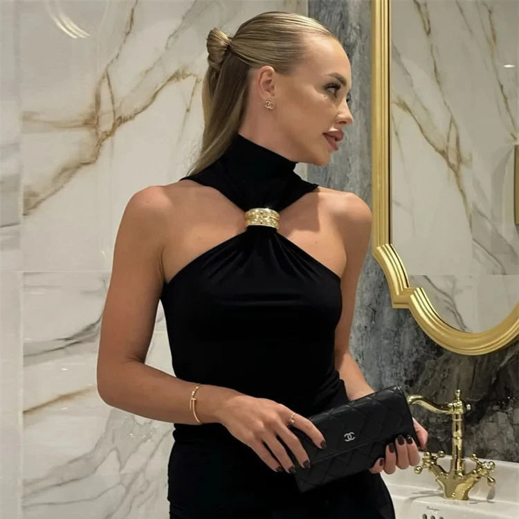 Woman in a black dress holding a Chanel clutch in a marble bathroom.