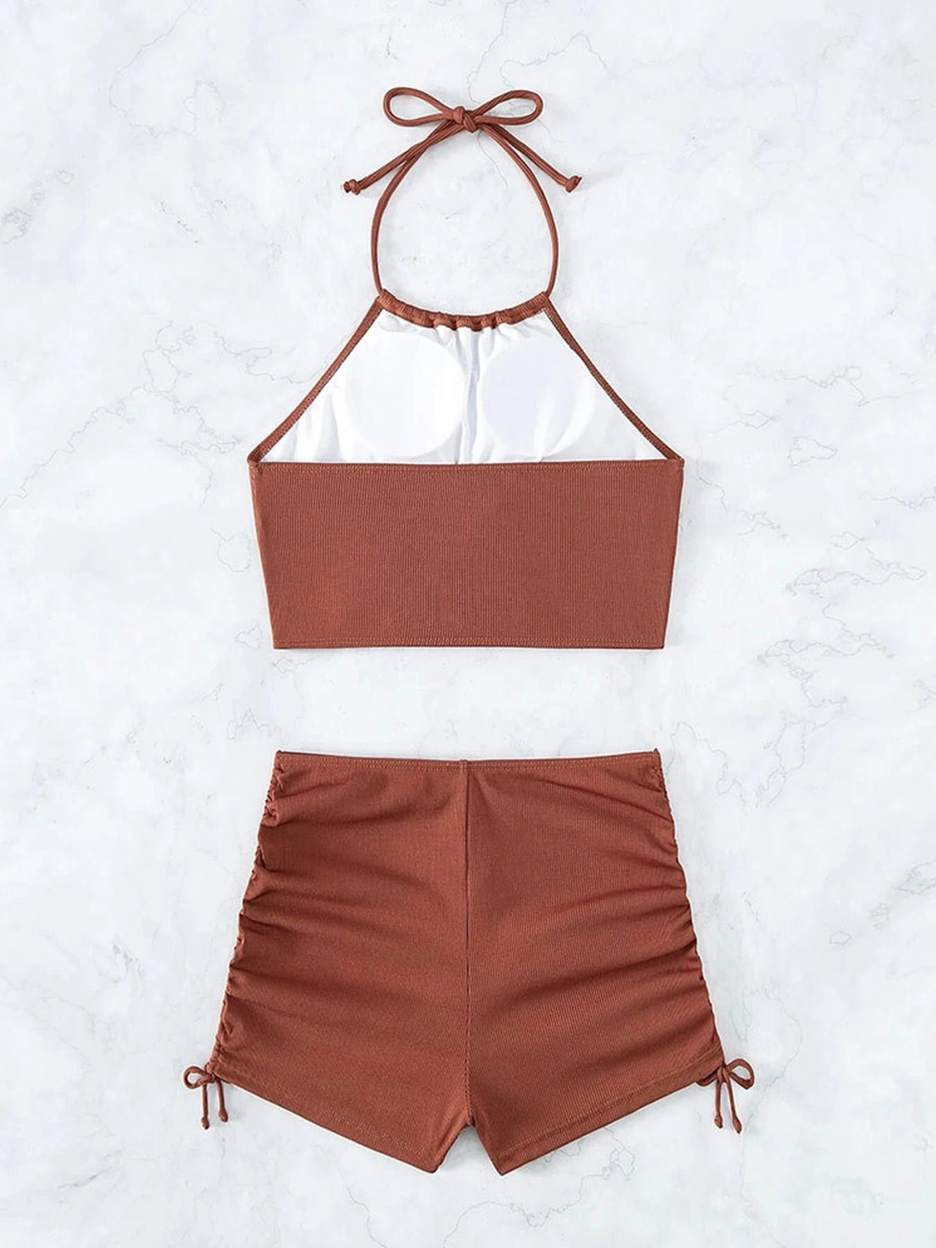 Brown bikini set with halter top and shorts on a white background