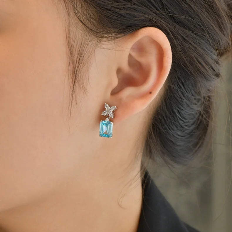 Close-up of an ear wearing a starfish and blue gemstone earring.