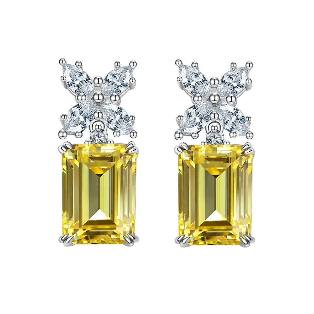 Pair of yellow gemstone earrings with diamond-like top elements on a white background