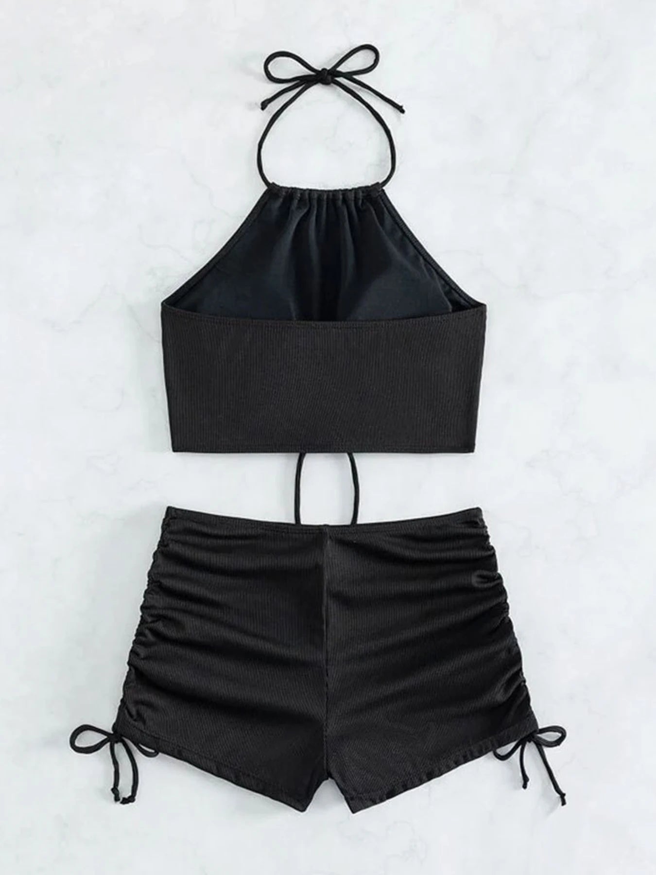 Black two-piece outfit with halter top and shorts on a white background