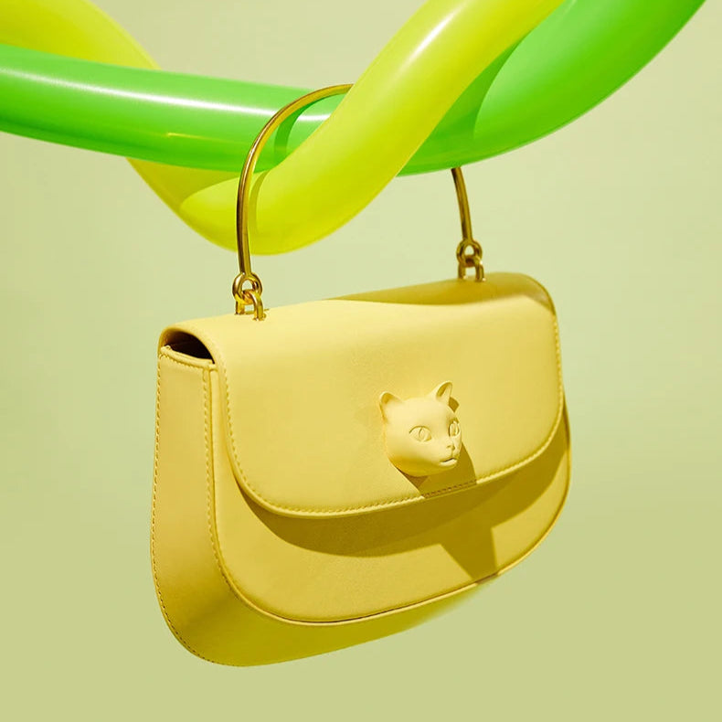 Yellow handbag with a cat design on a light green background, featuring the brand 'Nameless Cat'.