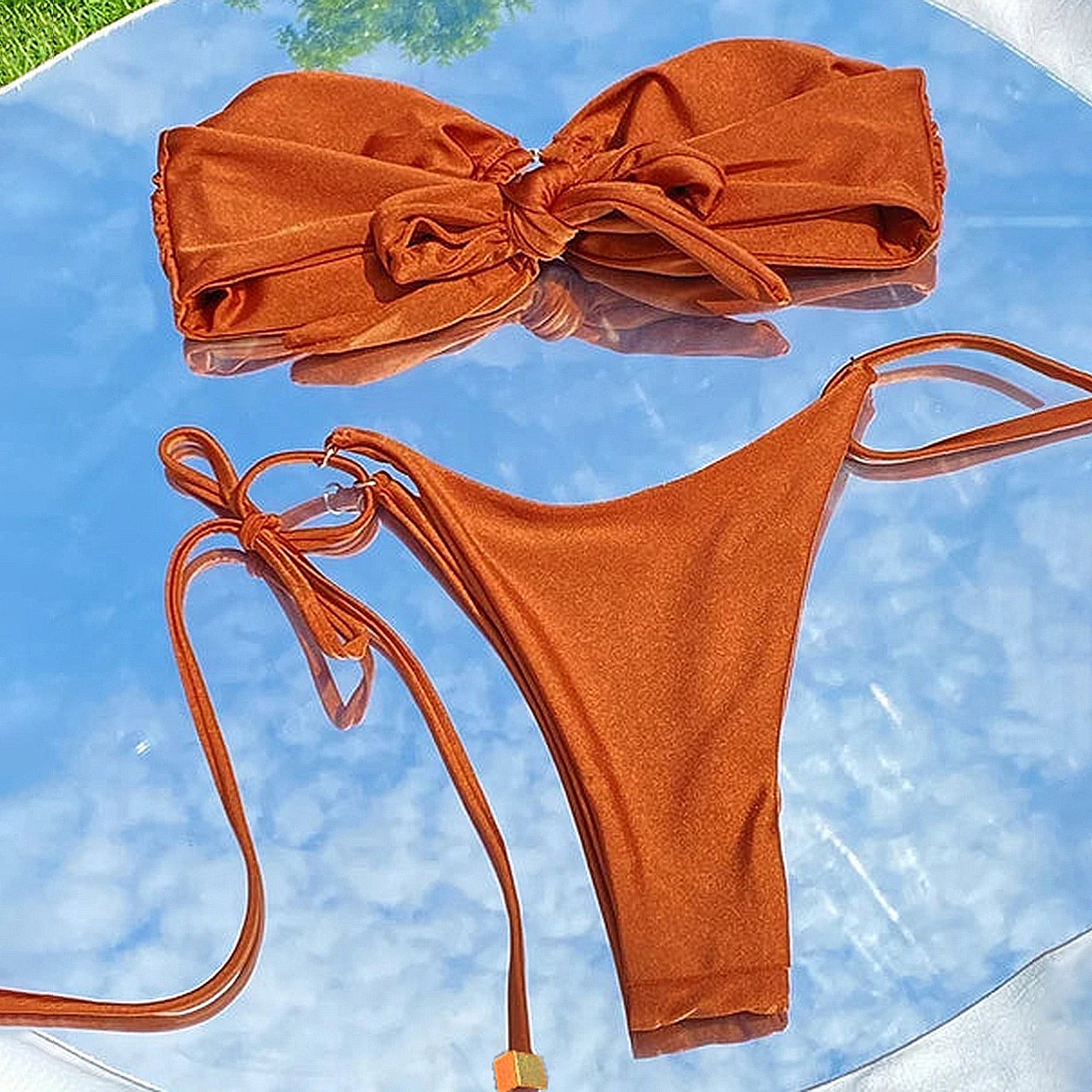 Brown bikini set on a reflective surface with a blue background