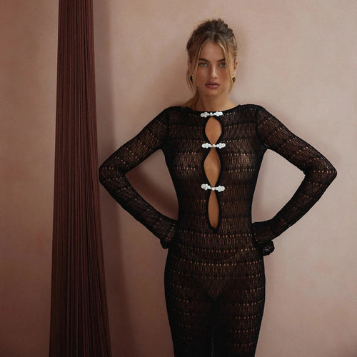 Woman wearing a black textured outfit with cut-out design against a pink wall.