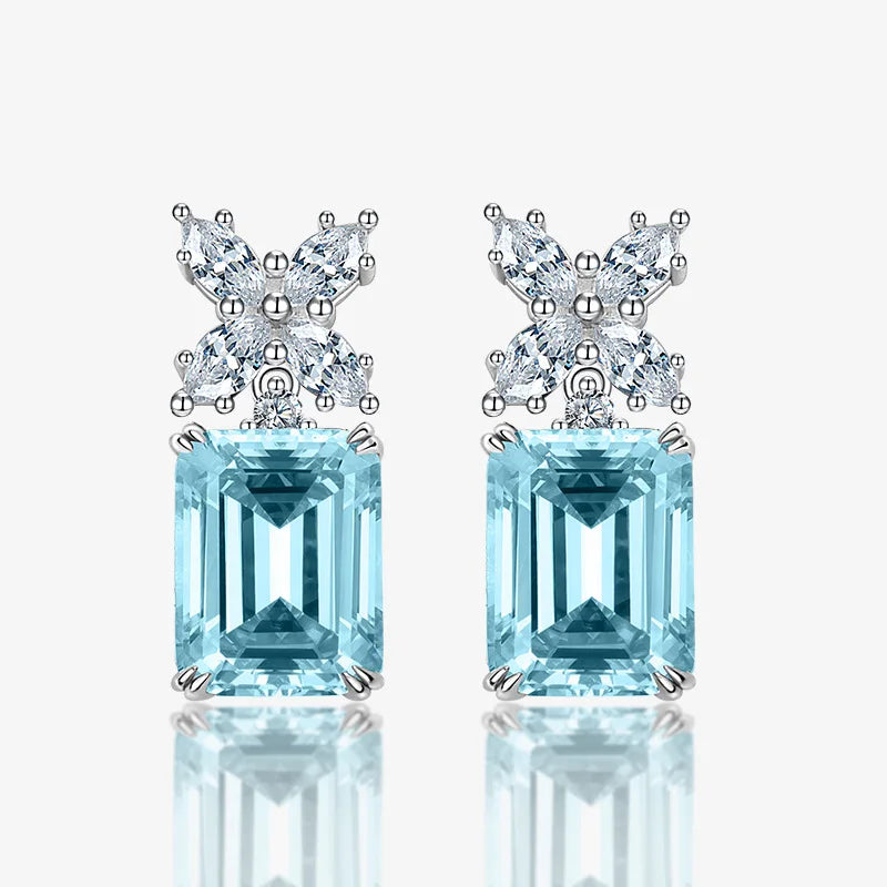 Pair of earrings with blue gemstones and butterfly-like top decorations on a white background