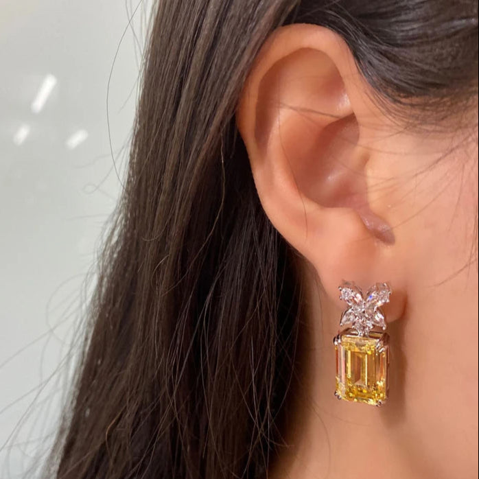 Close-up of an ear wearing a pair of diamond earrings with a neutral background